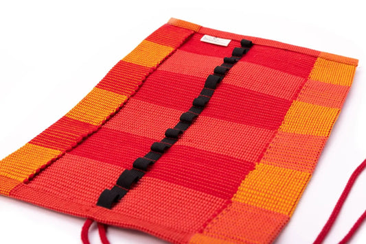 Red and Orange crayon roll up case open to show pockets on white background