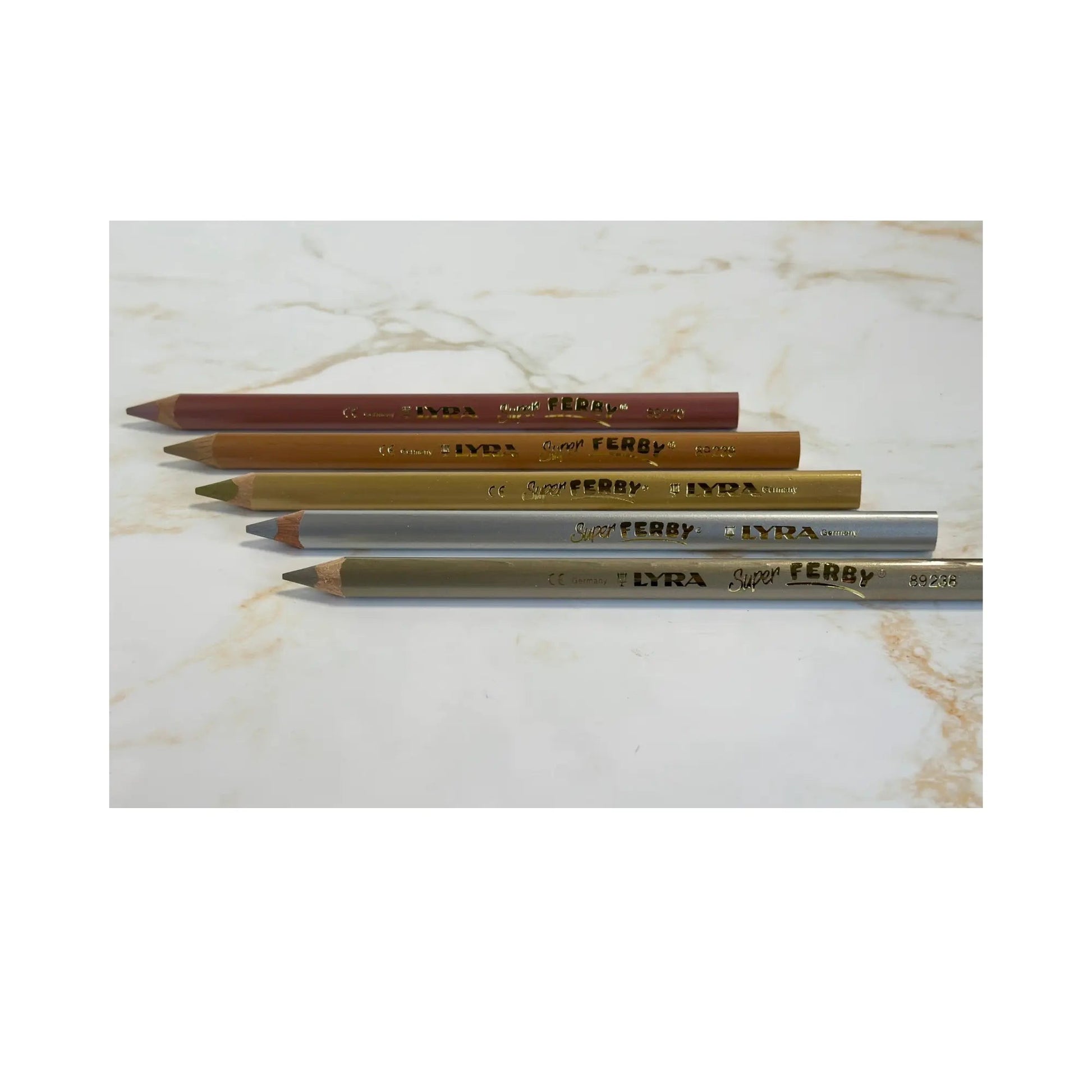 Four pencils of different colors on a marble surface