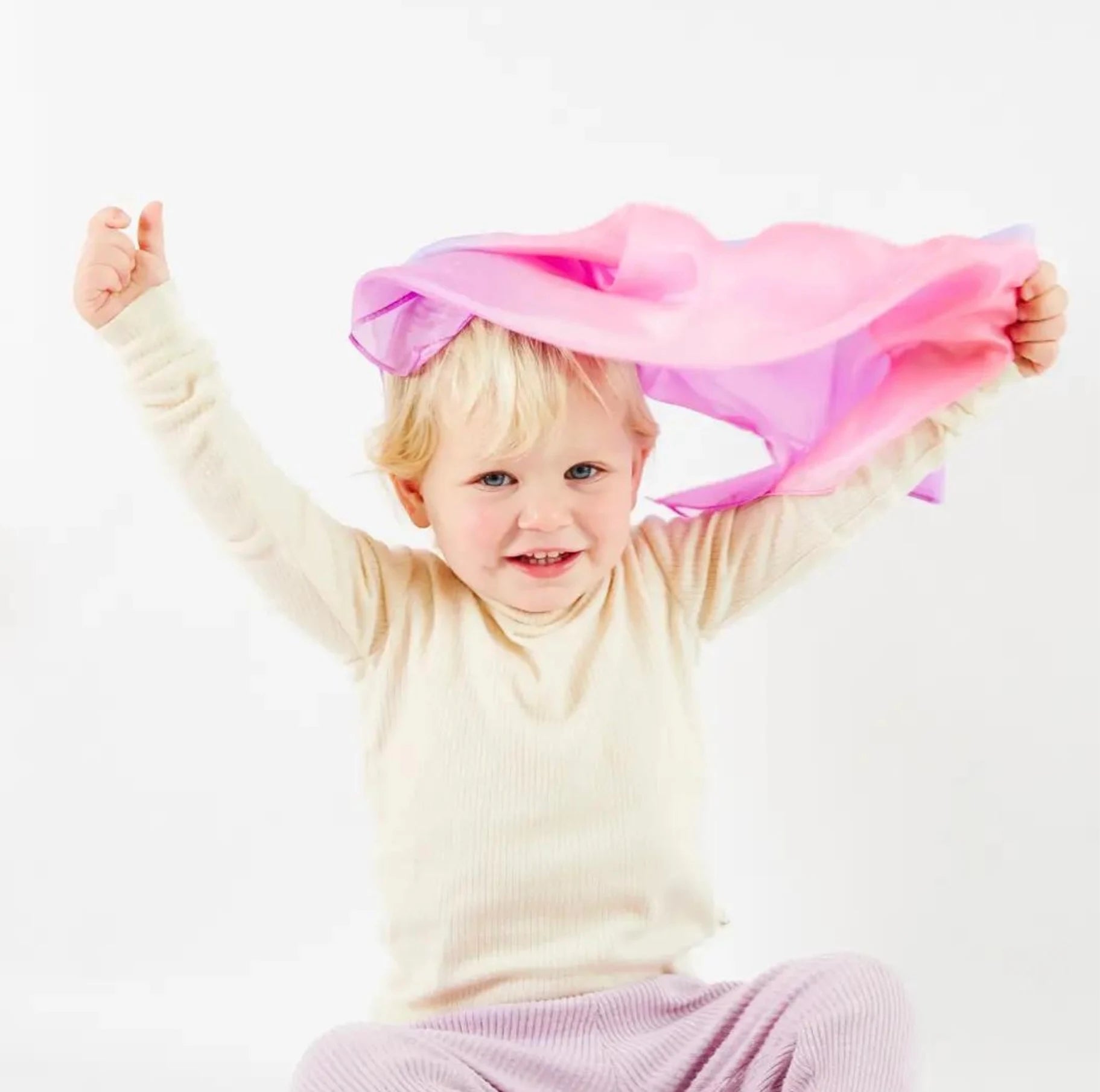 A toddler playing with Sarah’s Silks - Enchanted Playsilk in Blossom