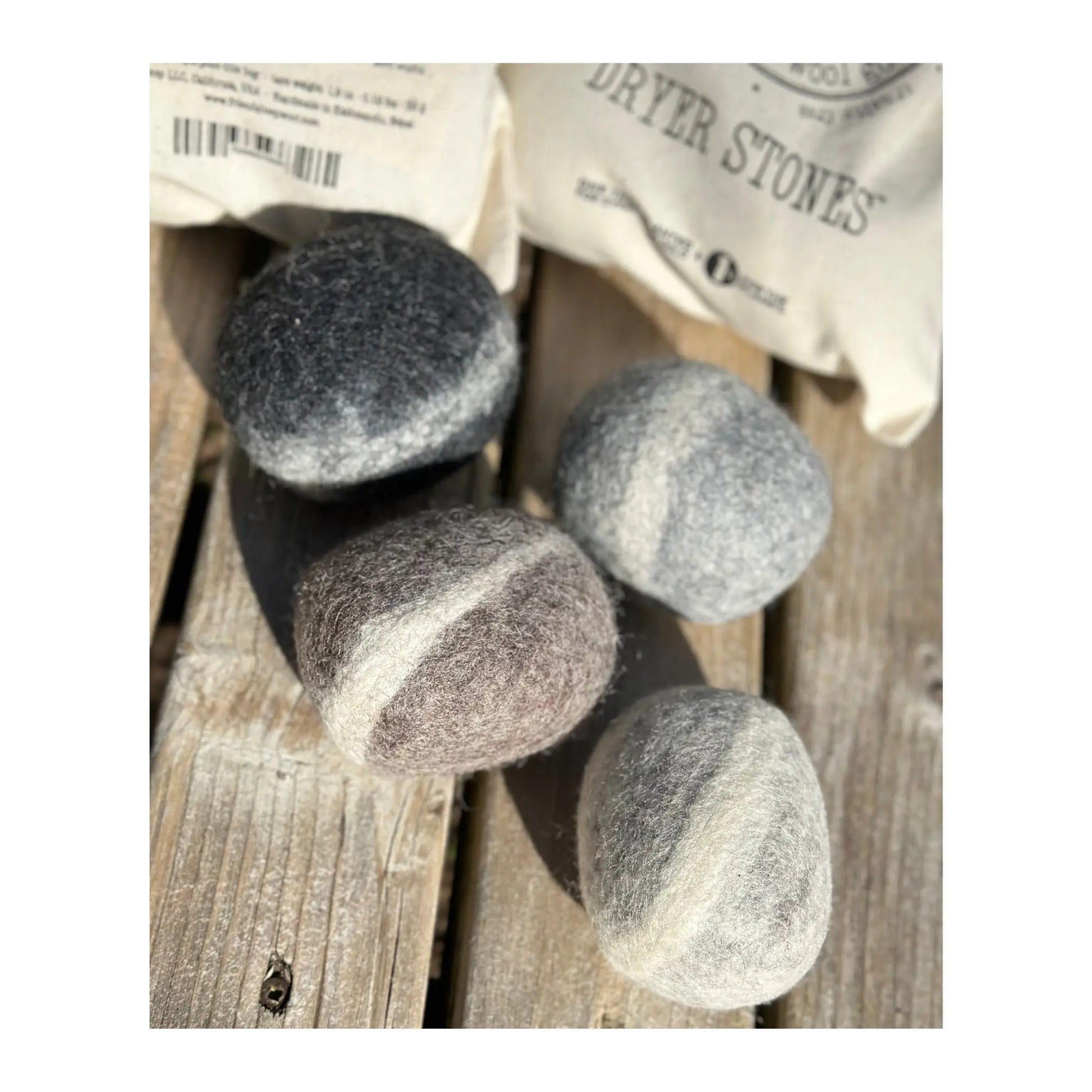 Set of gray dryer stones on a wooden surface with packaging in the background.