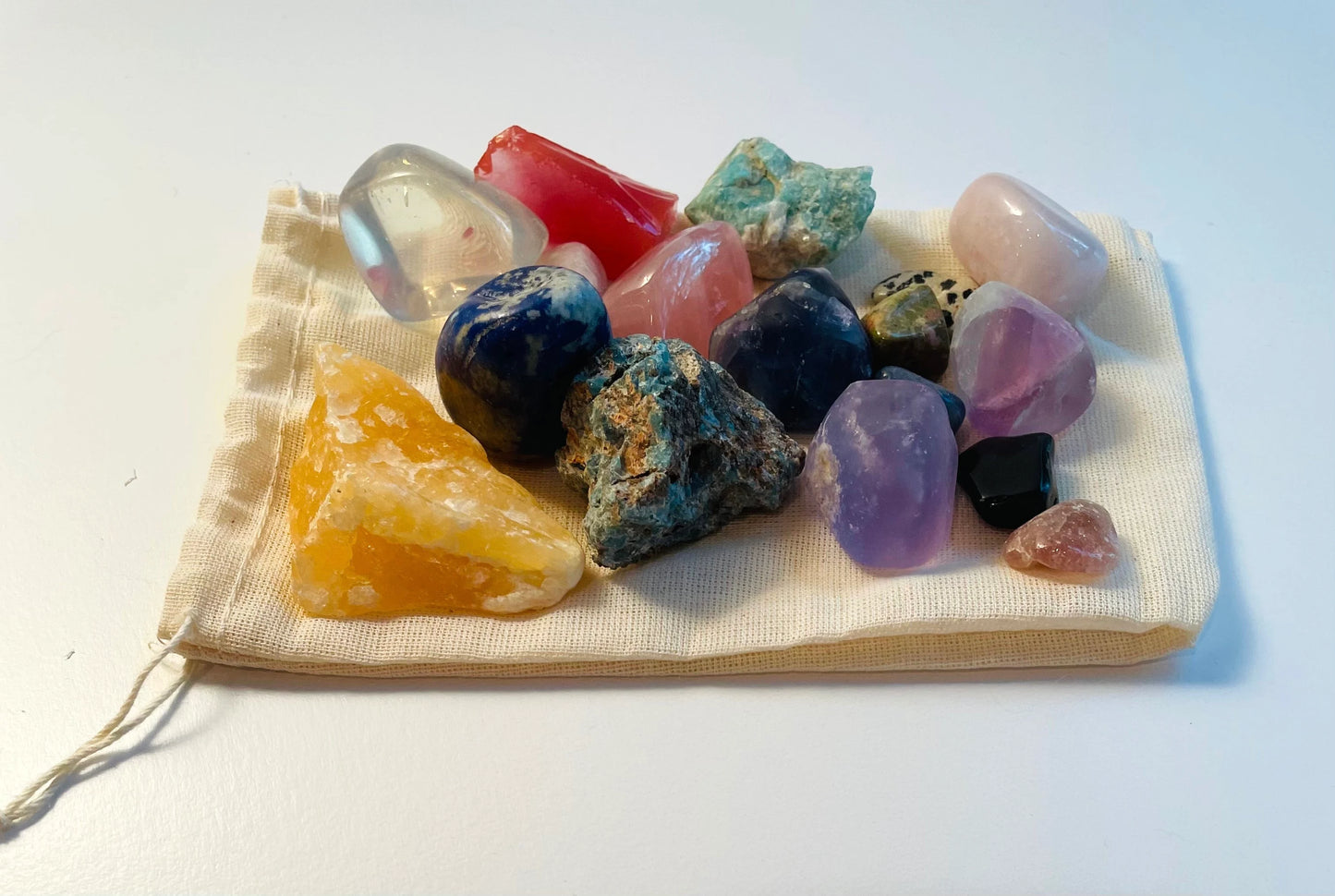 Variety of rocks raw and polished in different sizes on a drawstring bag