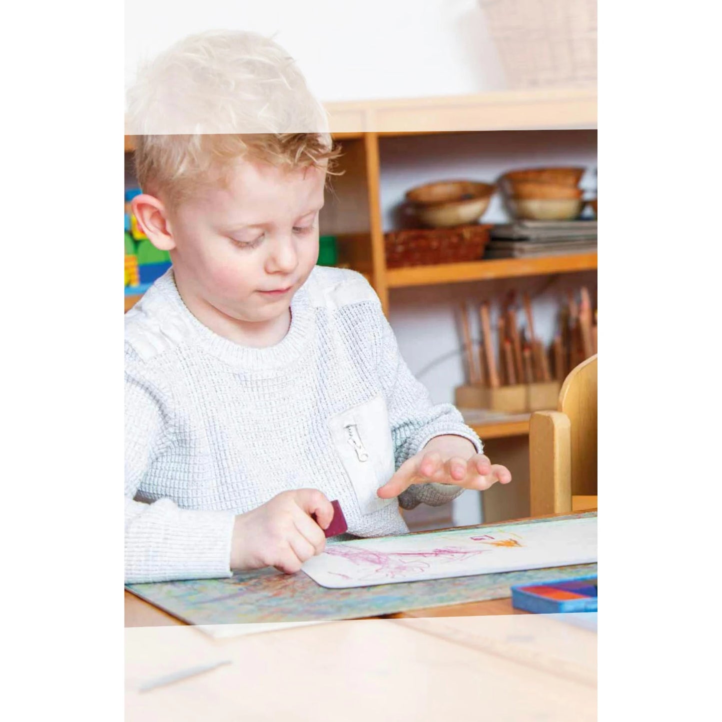 Child sitting at a table with Stockmar crayons in a classroom setting