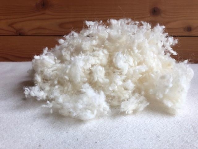 Clump of white wool on a wooden surface