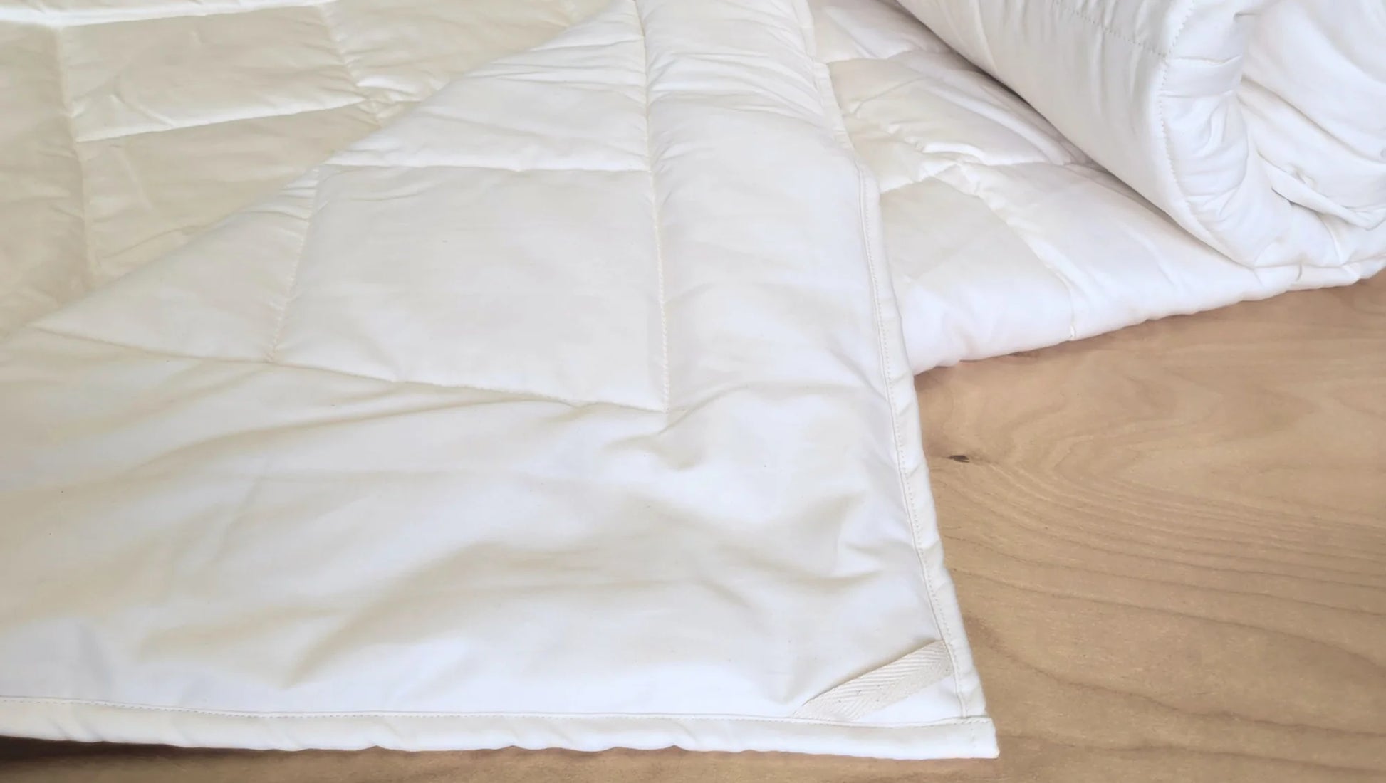 White comforter on a bed with a wooden headboard