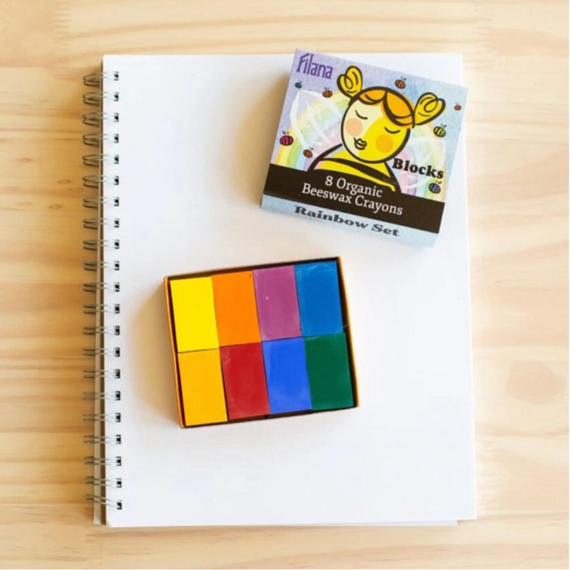 Set of colorful organic beeswax crayons on a notebook with their packaging.