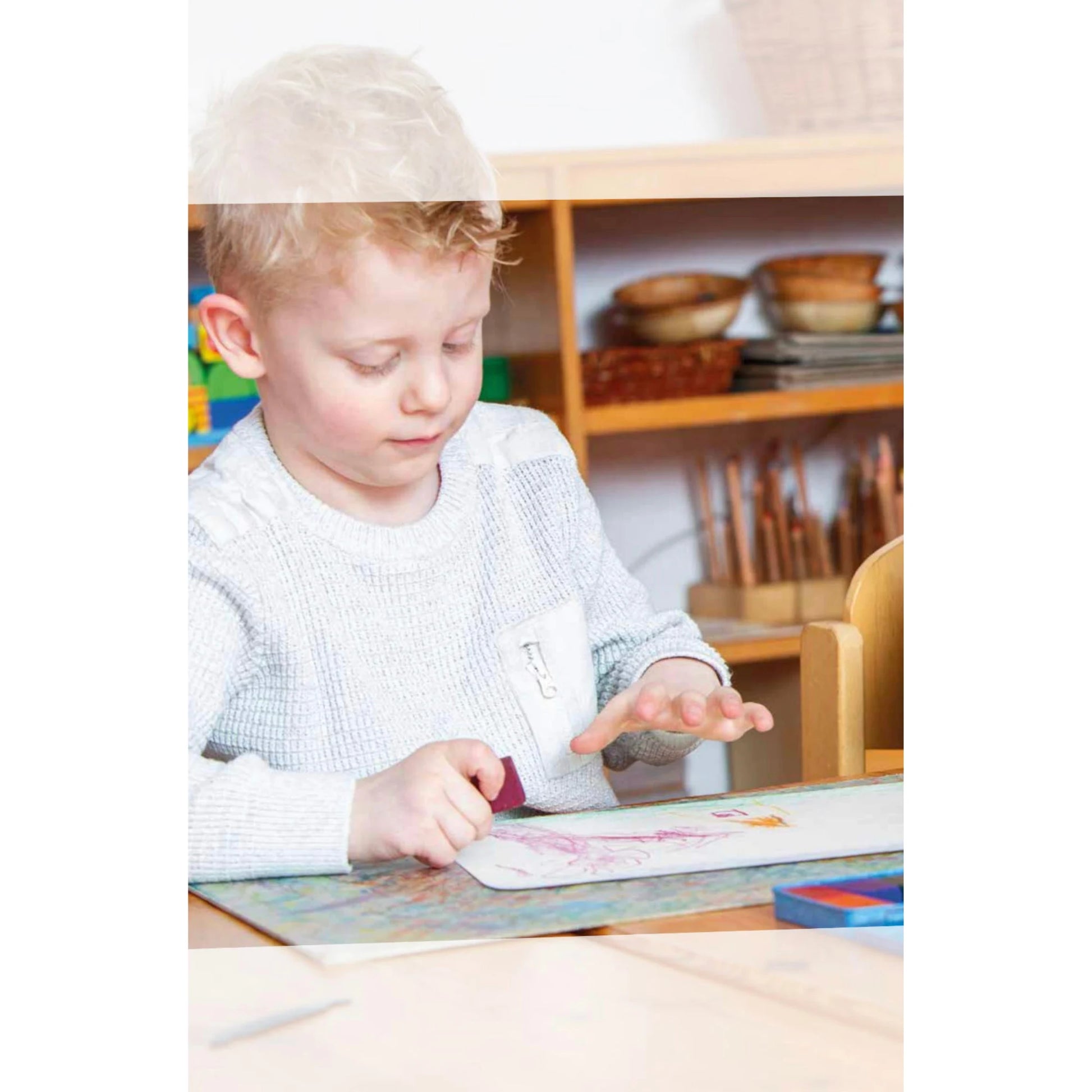 Child sitting at a table with Stockmar crayons in a classroom setting