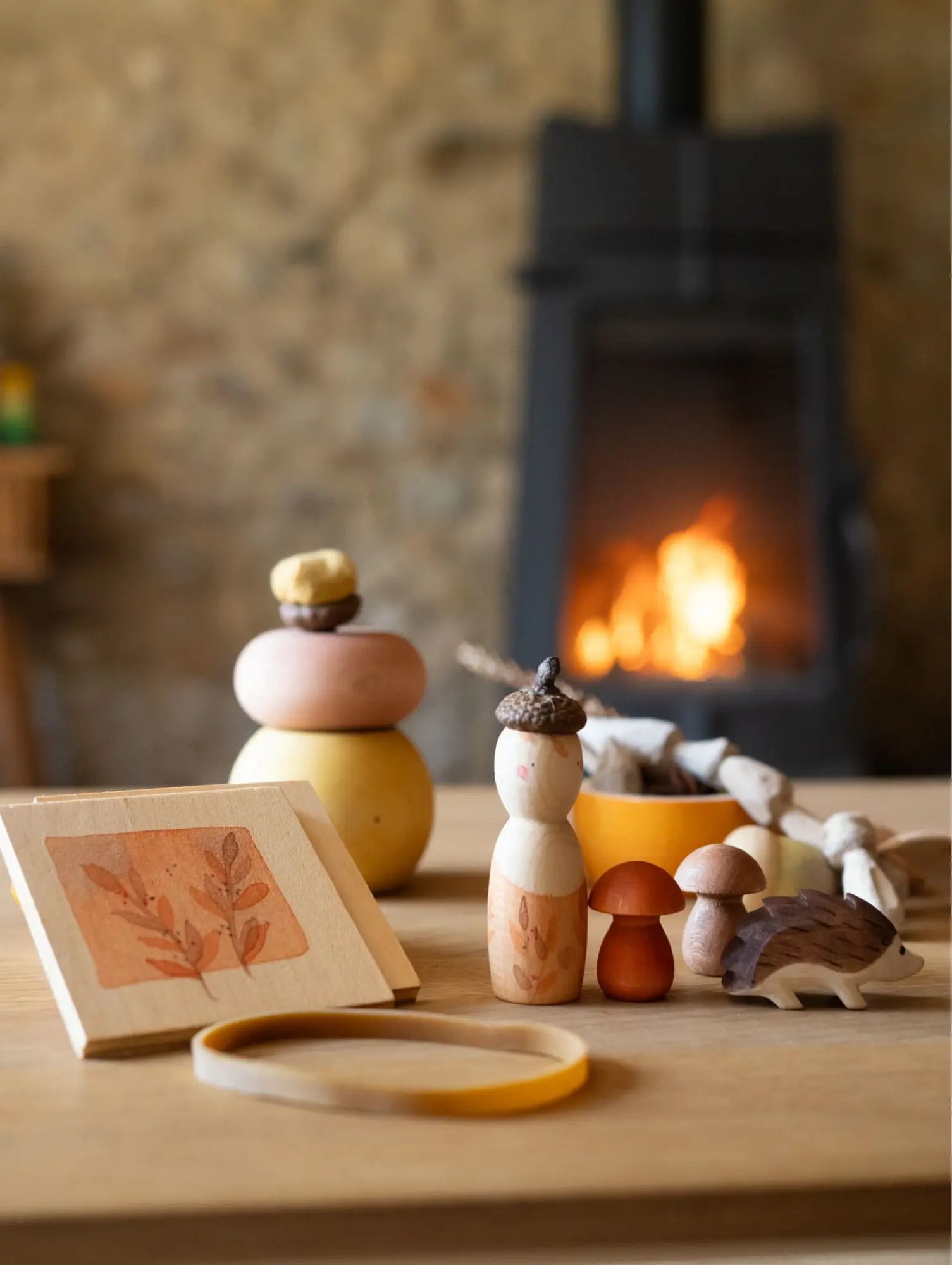 Imaginary play wooden toys and decor items on a table with a fireplace in the background